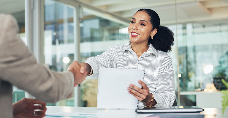 professional woman at desk shaking hands
